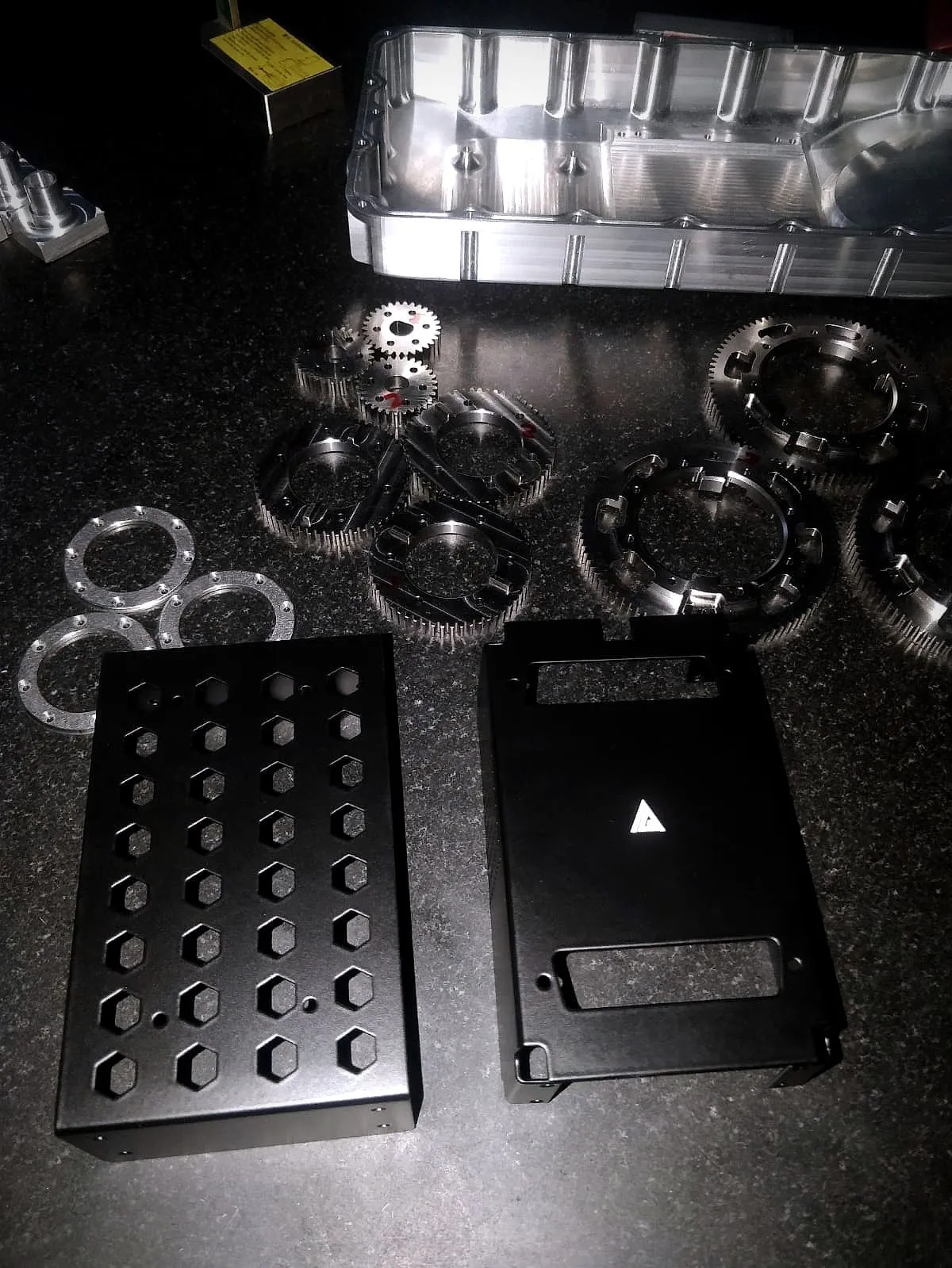 Machined gears, rings, a housing and black anodised enclosures on granite