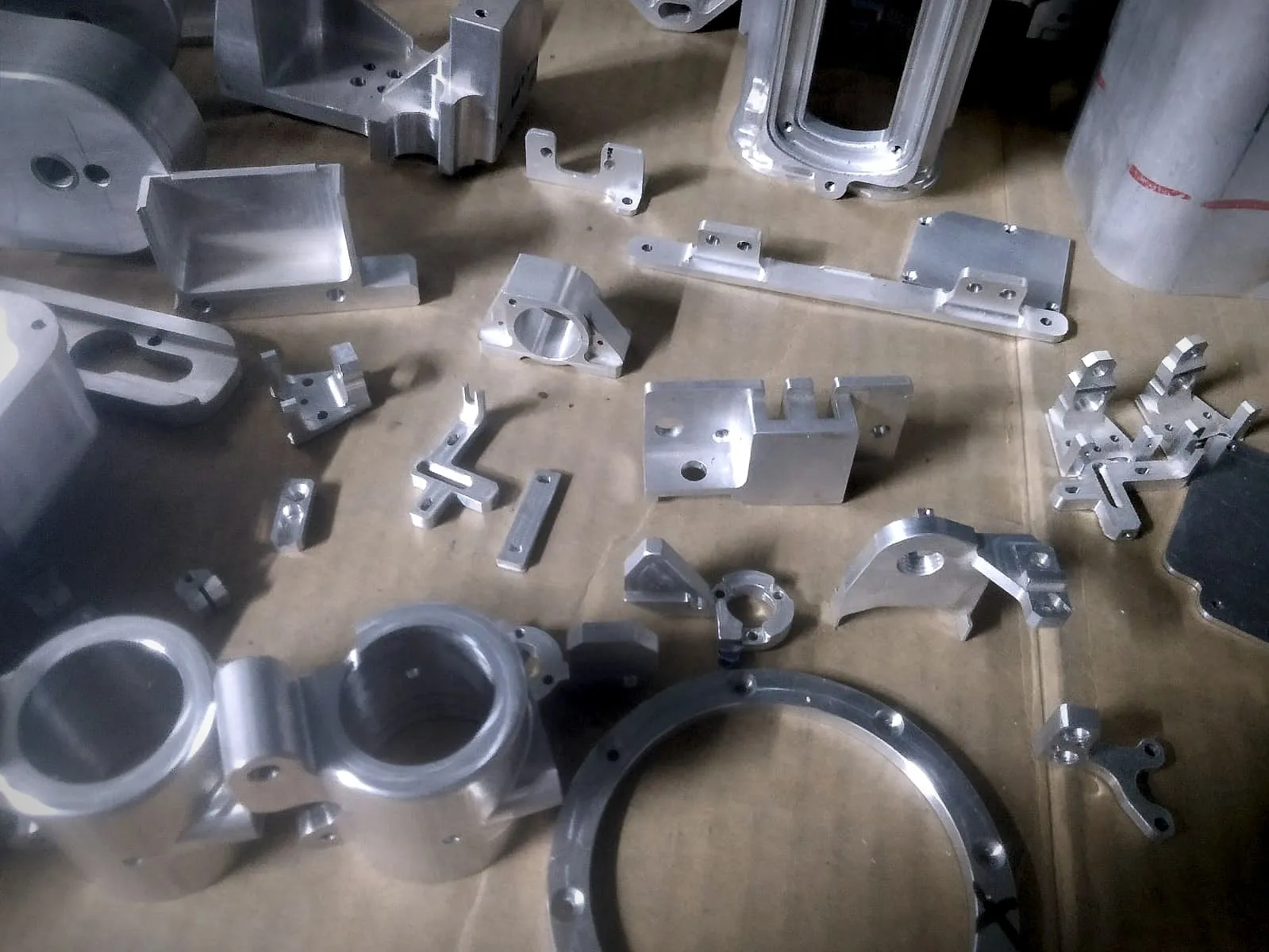 A range of precision-machined aluminium brackets, blocks, rings and housings laid out on the shop floor