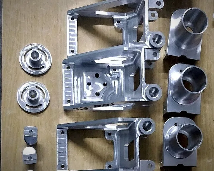 Finished machined aluminium brackets and flanged cups laid out for inspection